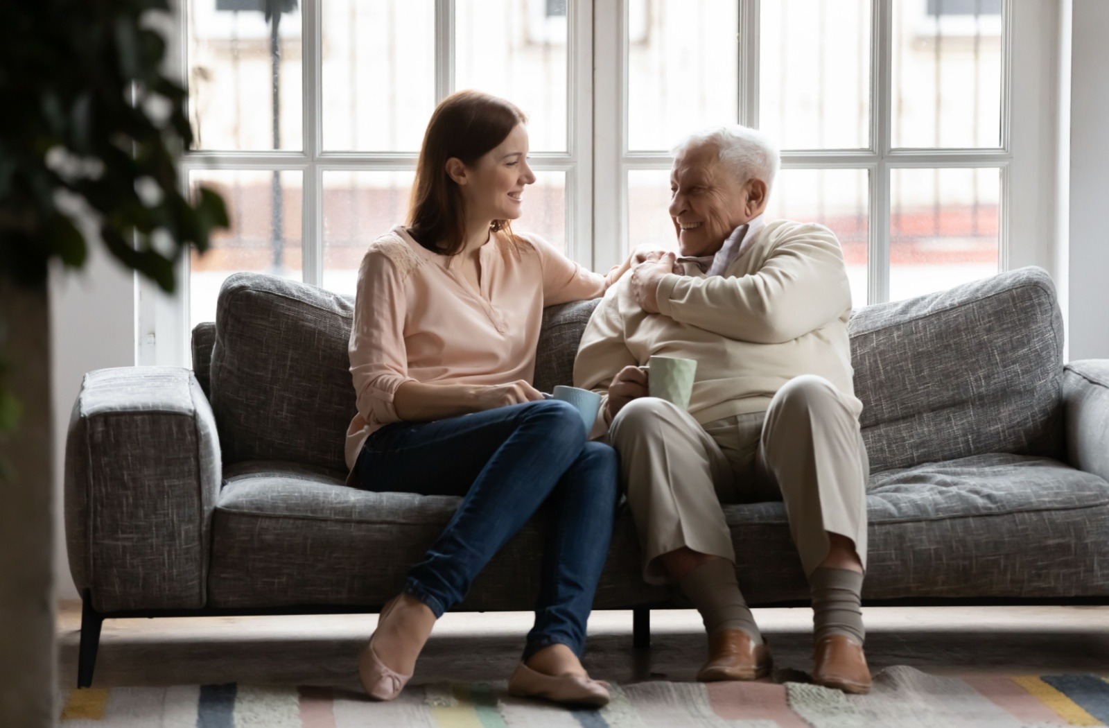 a senior and their adult child sitting on a couch smiling